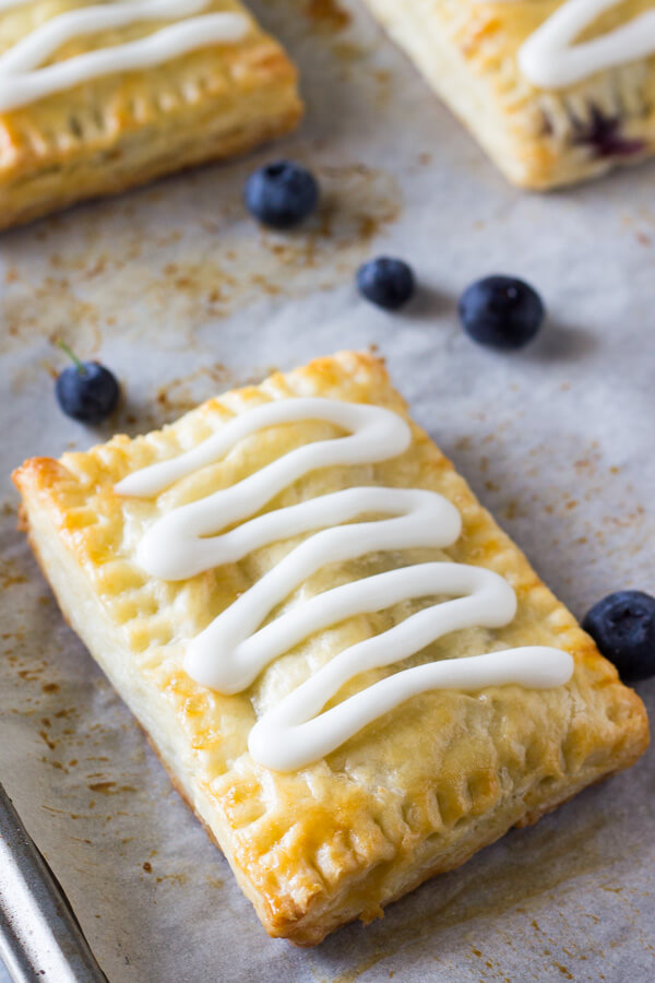 Buttery, flaky homemade blueberry toaster strudels with juicy blueberry centers and sweet vanilla glaze. 1000 times better than the store bought variety - learn to make them at home!