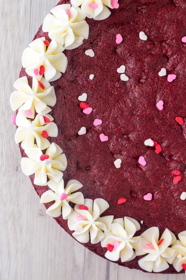Red Velvet Cookie Cake. A giant red velvet chocolate chip cookie made into a cake and frosted with cream cheese frosting. Made from scratch & perfect for Valentine's or Christmas. www.justsotasty.com