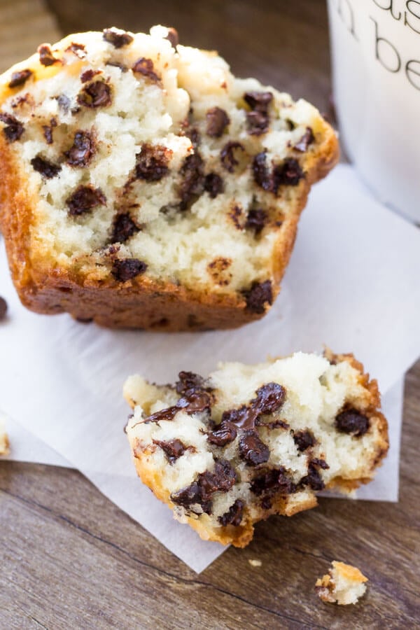 A big, fluffy bakery-style chocolate chip muffin broken in half. 