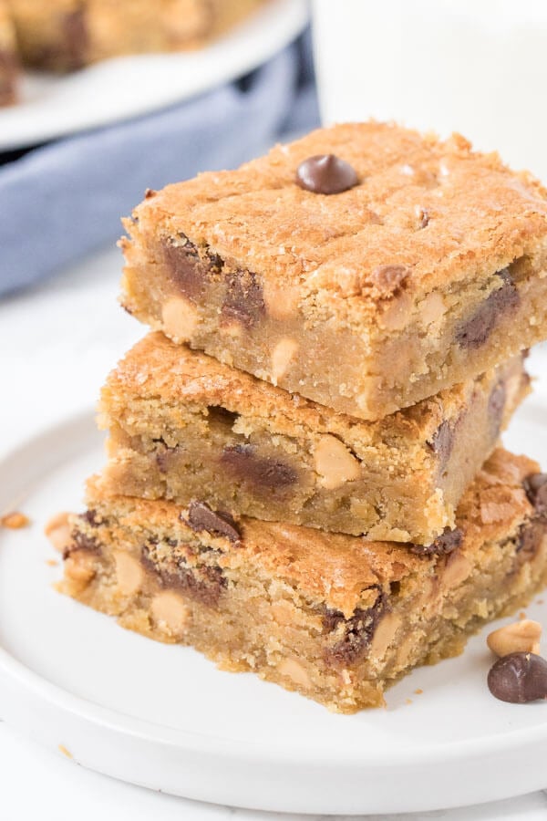 A stack of 3 chewy peanut butter blondies with peanut butter chips and chocolate chips. 