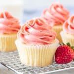 Vanilla cupcakes with strawberry frosting on a wire rack