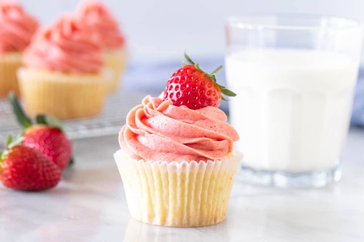 Vanilla cupcake with fresh strawberry frosting and a strawberry on top