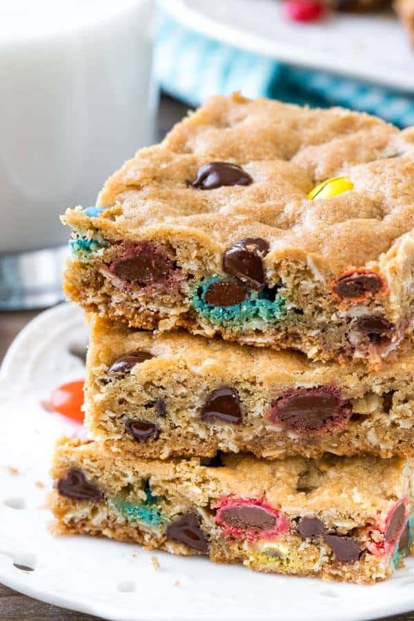 A stack of 3 monster cookie bars on a white plate. 