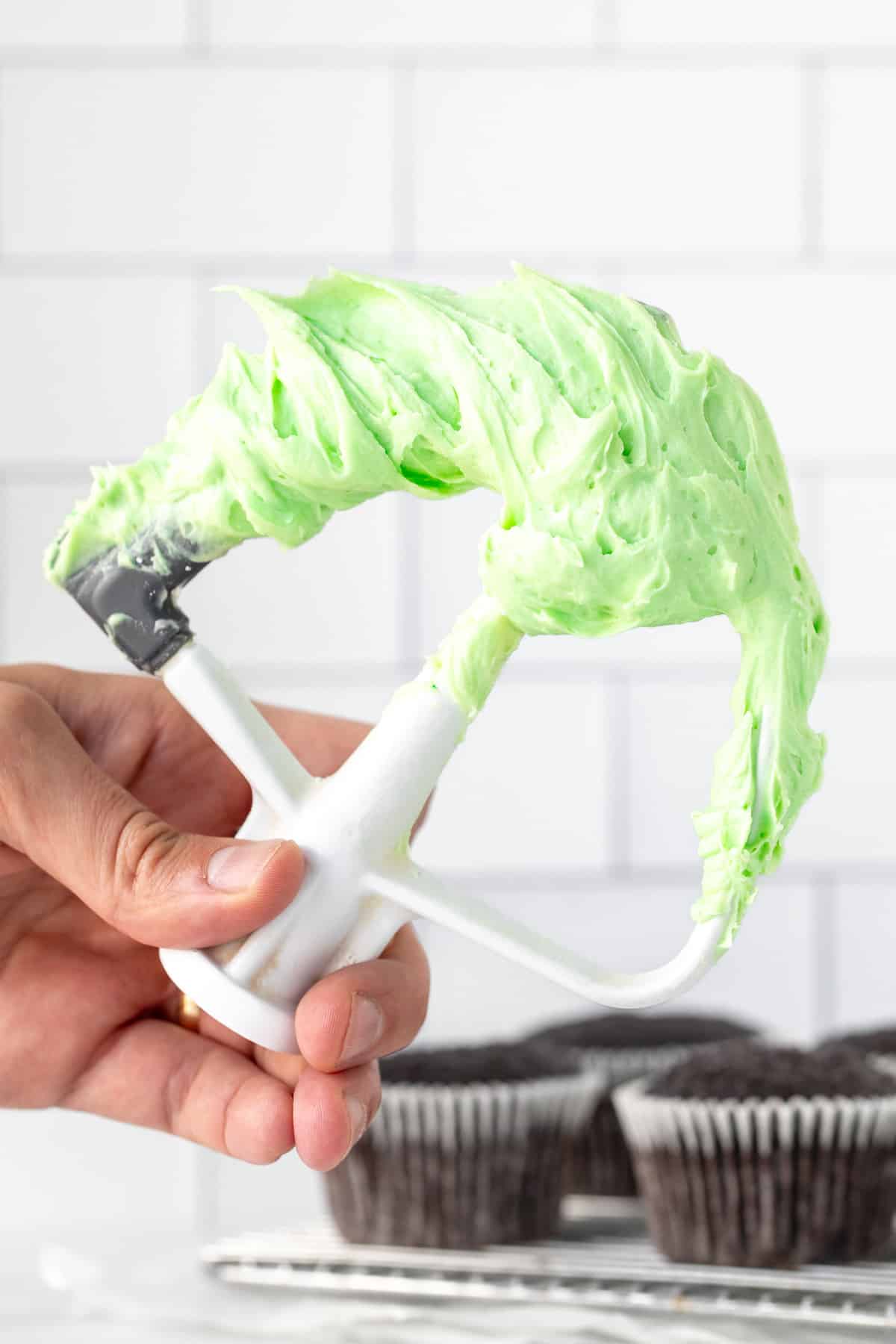 Stand mixer beater covered in mint frosting