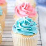 Vanilla cupcakes with colored frosting on a cooling rack.