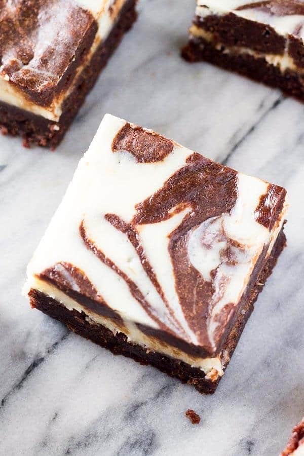 A close up shot of a fudgy, cream cheese brownie with swirls of brownie and cheesecake. 