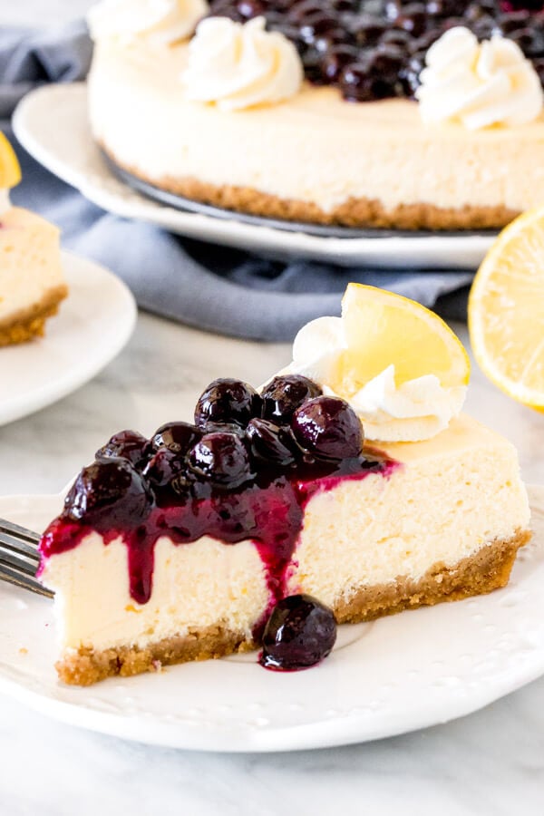 Slice of lemon cheesecake topped with blueberry sauce on a plate. 