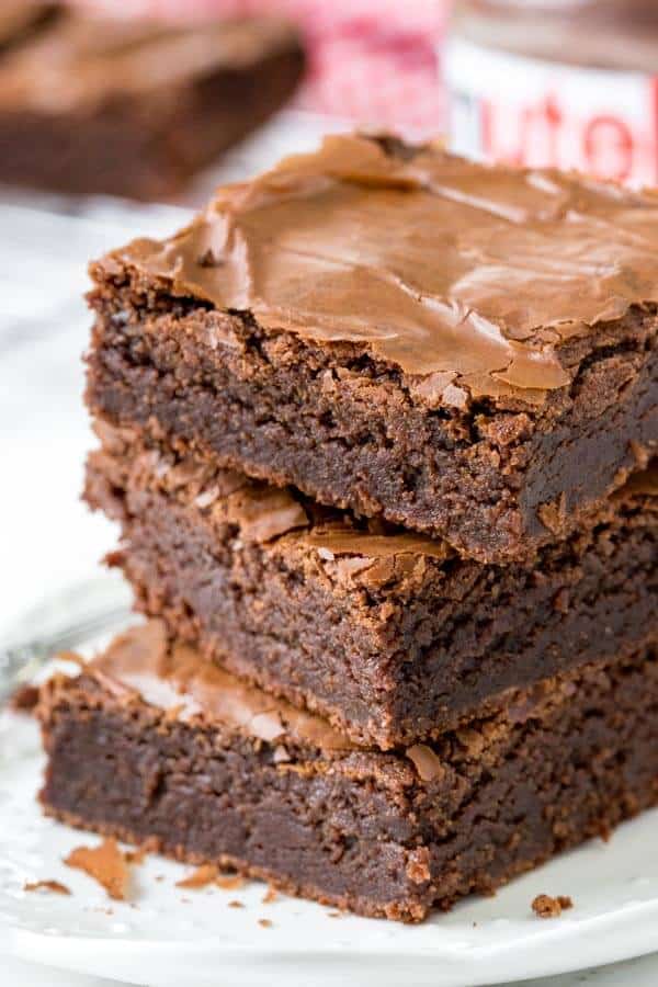 A stack of 3 fudgy Nutella brownies on a white plate. 