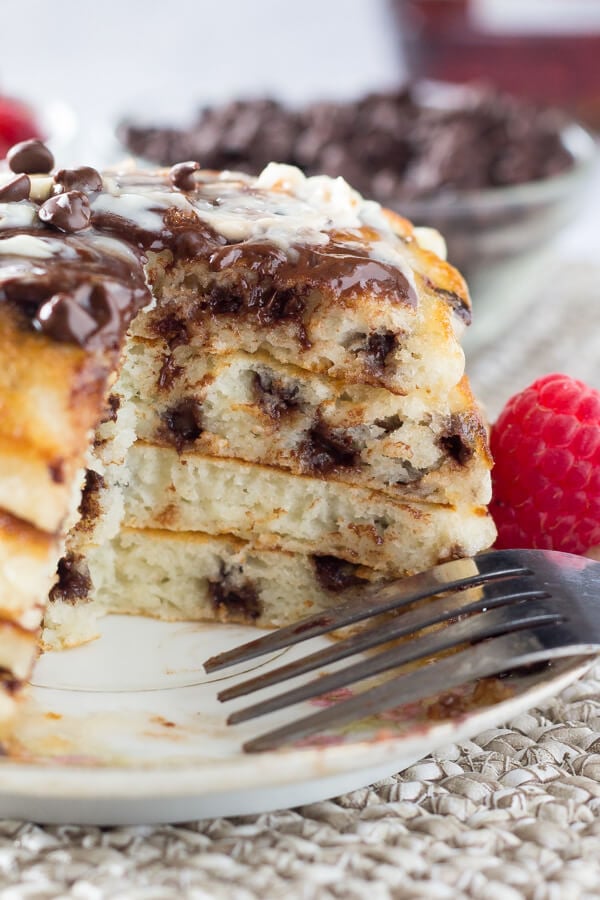 A side view of a large stack of chocolate chip pancakes with a bite taken out of them. 