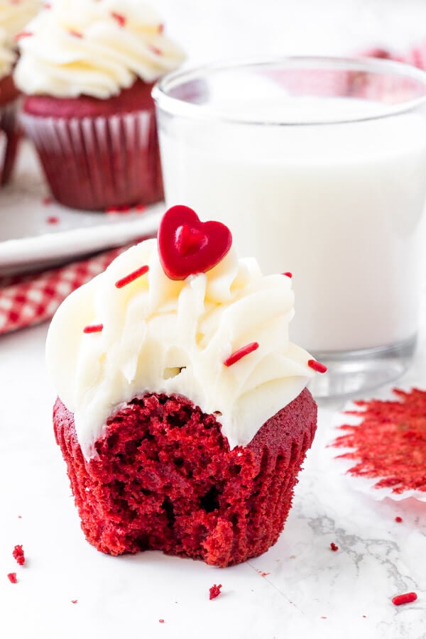 Red velvet cupcake with cream cheese frosting and a bite taken out of it. Simply the best red velvet cupcake recipe. 