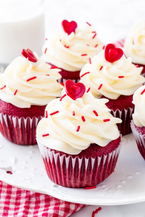A plate of red velvet cupcakes with cream cheese frosting & sprinkles