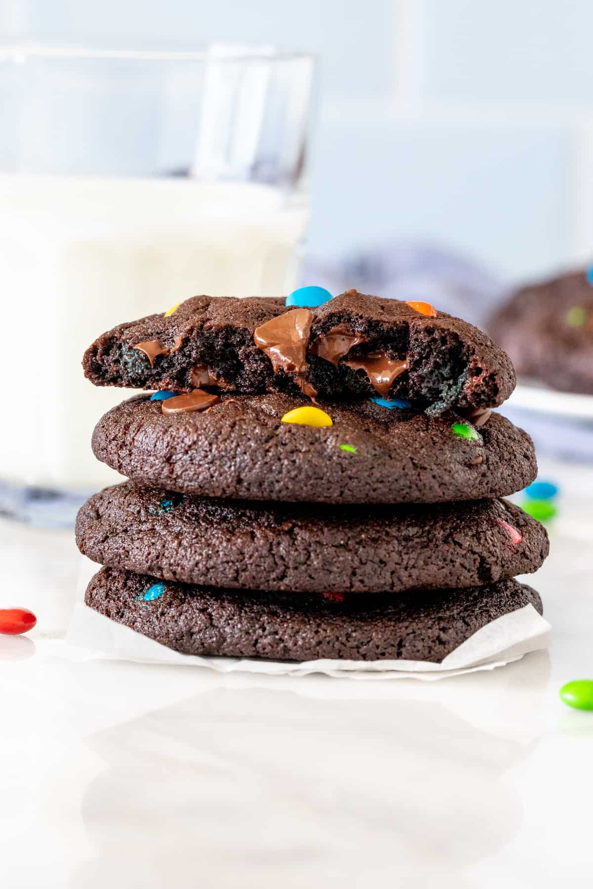 Stack of chocolate M&M cookies with glass of milk