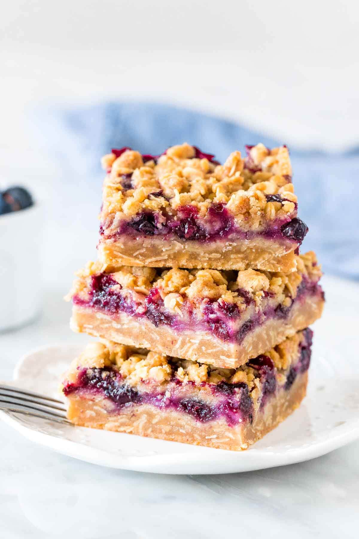 Stack of 3 blueberry oatmeal crumb bars on a plate. 