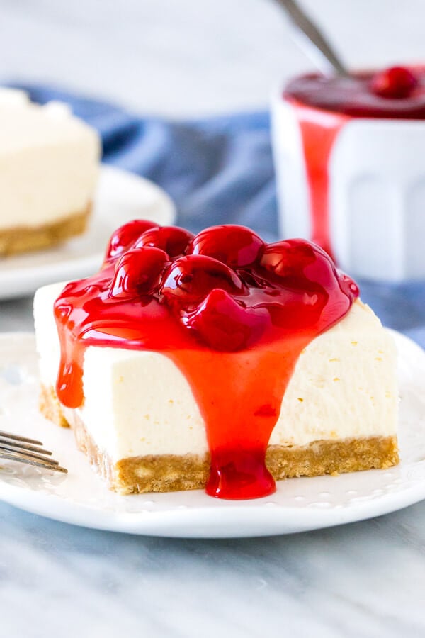 A slice of no bake cheesecake with cherry pie topping.