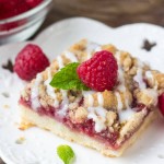 Raspberry Crumble Bars. These Raspberry Crumble Bars are filled with juicy berries, crunchy crumble & have a delicious hint of cinnamon. Delicious with a spoonful of vanilla ice cream, or a drizzle of vanilla glaze! www.justsotasty.com