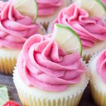 Group of lime cupcakes with raspberry frosting with a lime slice on top.