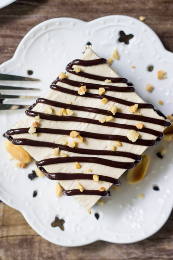 Overhead shot of peanut butter ice cream drumstick cake on a white plate and drizzled with chocolate sauce and chopped peanuts. 