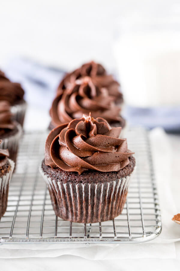 Chocolate cupcakes with chocolate frosting on a cooling rack. 