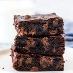Stack of 3 chewy brownies with a glass of milk.