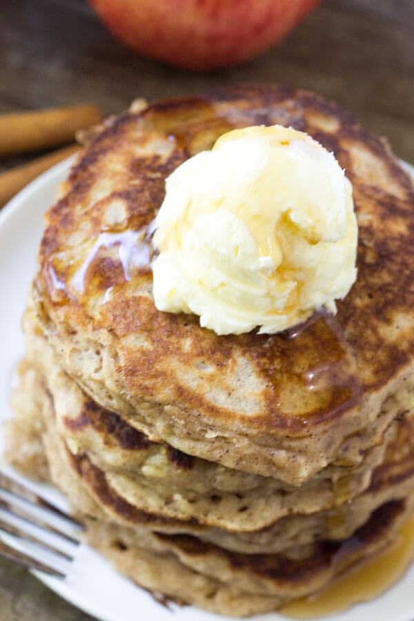 Overhead shot of stack of apple pancakes with whipped butter and maple syrup