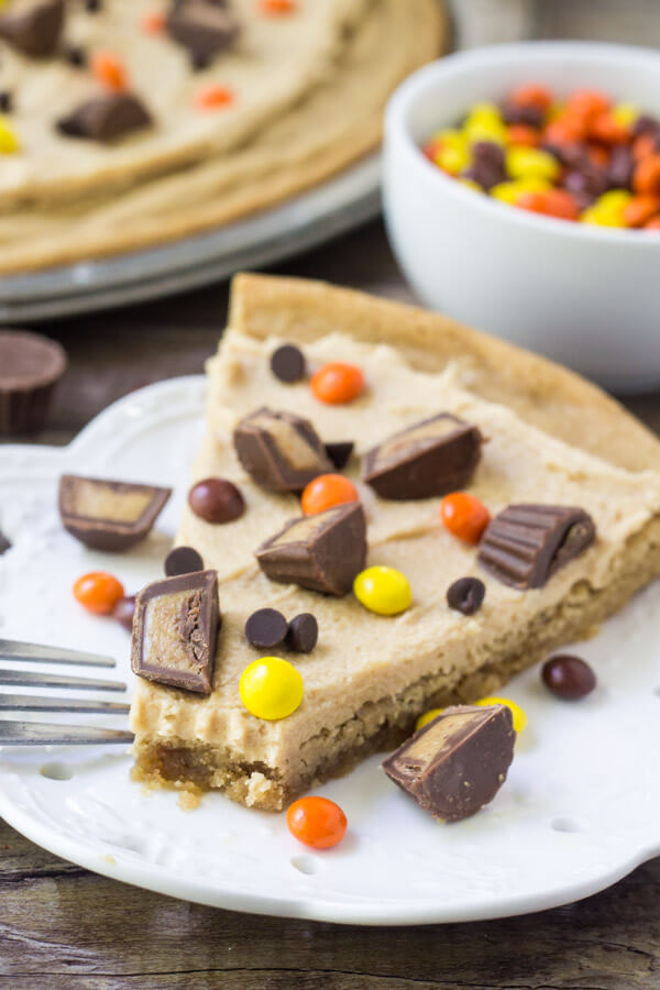 Slice of peanut butter cookie pizza with a soft and chewy peanut butter cookie base, peanut butter frosting and peanut butter candies. 