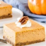 A slice of creamy pumpkin cheesecake bars taken from the side to show the creamy, smooth texture.