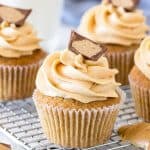 Peanut butter cupcakes on a cooling rack topped with a peanut butter cup.