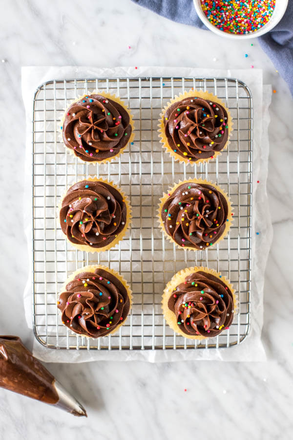 6 cupcakes with chocolate frosting on a cooling rack.