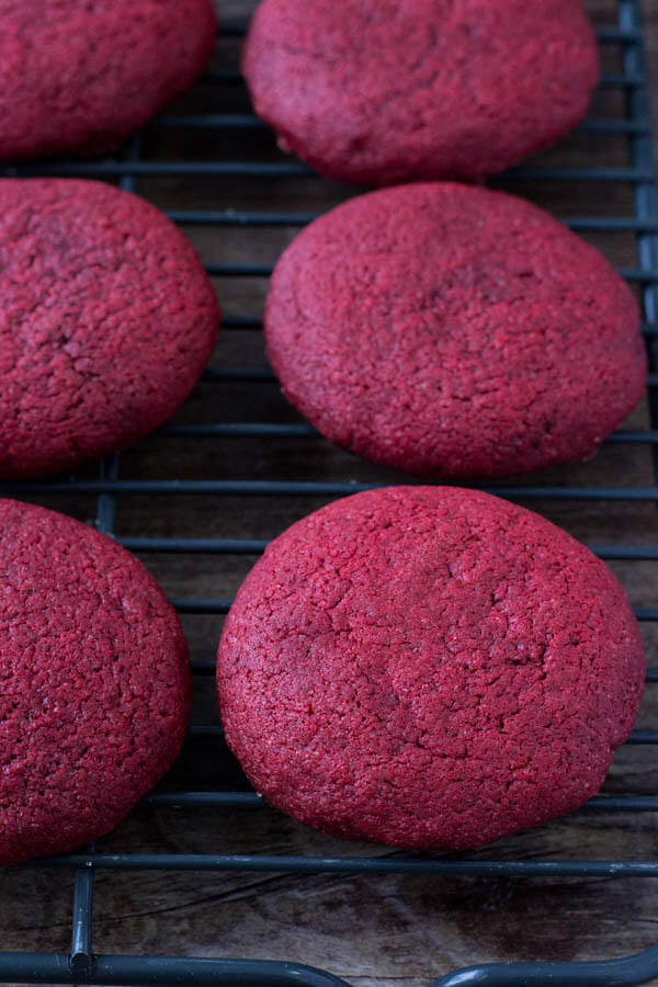 Freshly baked, soft red velvet cookies on a cooling rack. 