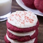 A stack of three red velvet cookies with cream cheese frosting.