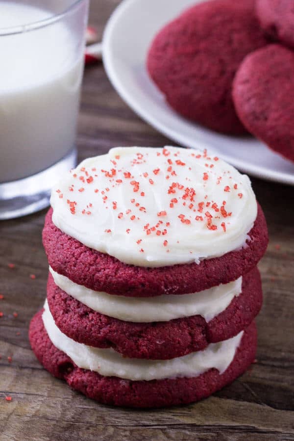 A stack of three red velvet cookies with cream cheese frosting. 