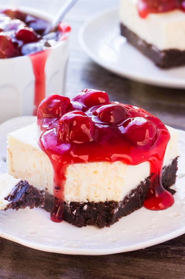 A slice of brownie bottom cheesecake with a bite taken out of it. 