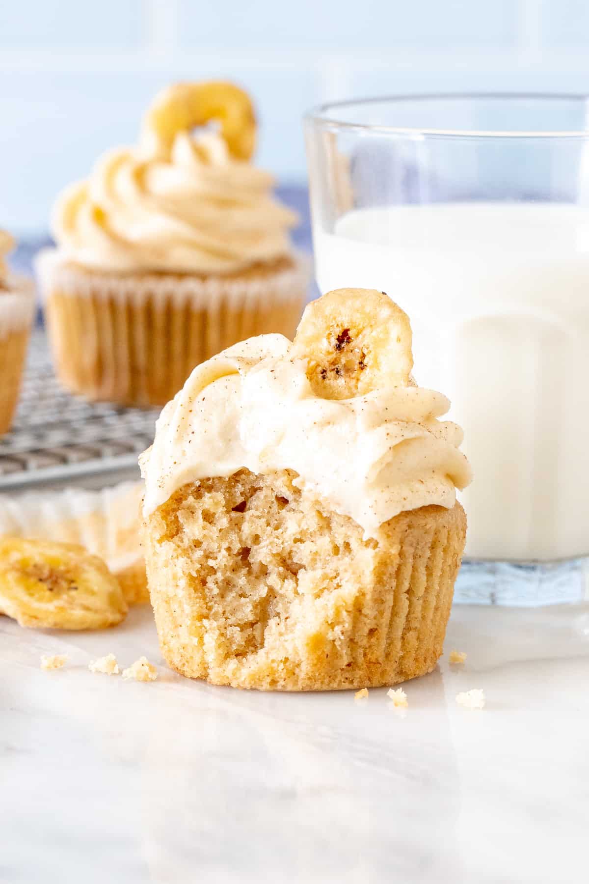 Banana bread cupcake with frosting on top with a bite taken out of it