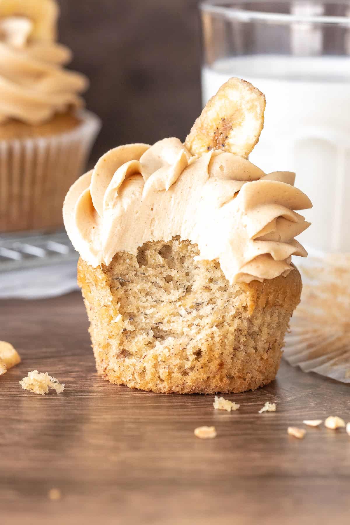 Cupcake topped with frosting and a banana chip with a bite taken out