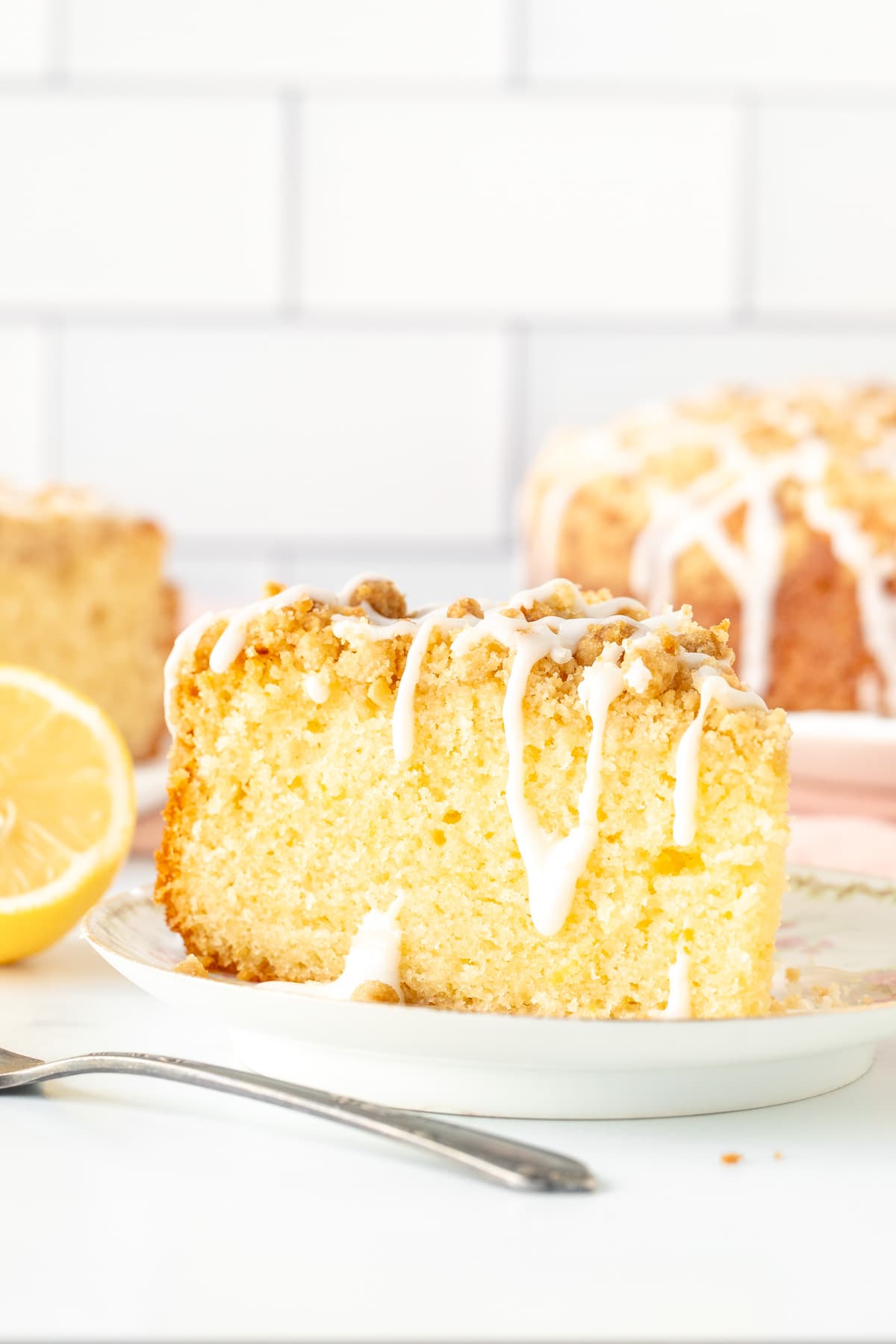 Slice of lemon coffee cake with crumb topping and drizzle of glaze