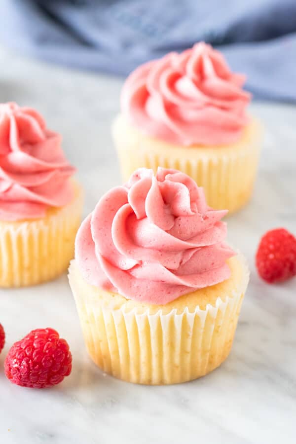 3 vanilla cupcakes with raspberry frosting.