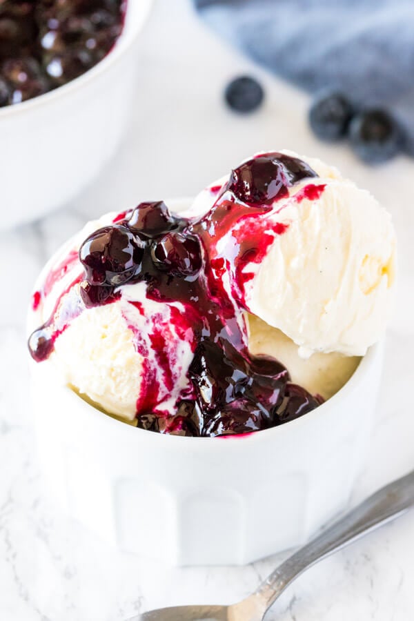 A bowl of vanilla ice cream topped with blueberry sauce, with the warm blueberry sauce gently melting the ice cream 