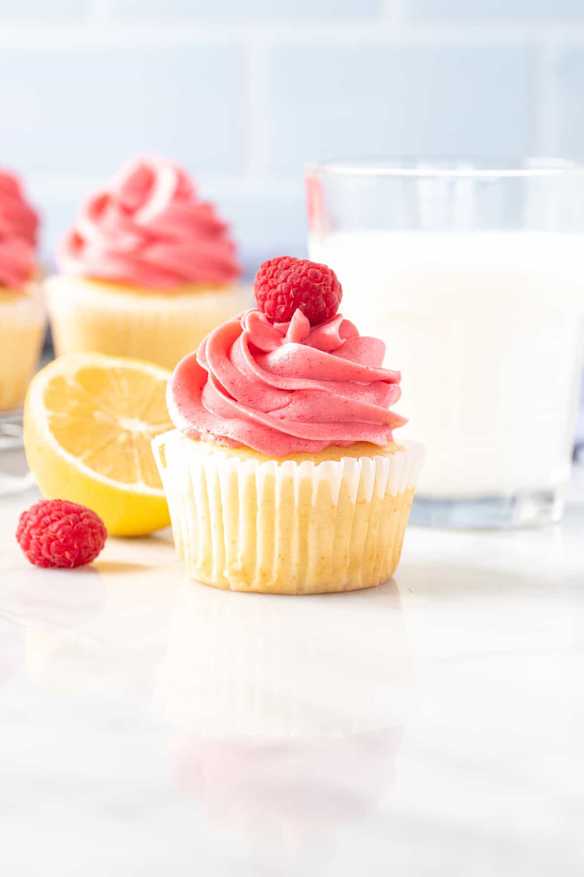 Lemon cupcake with pink frosting with a glass of milk