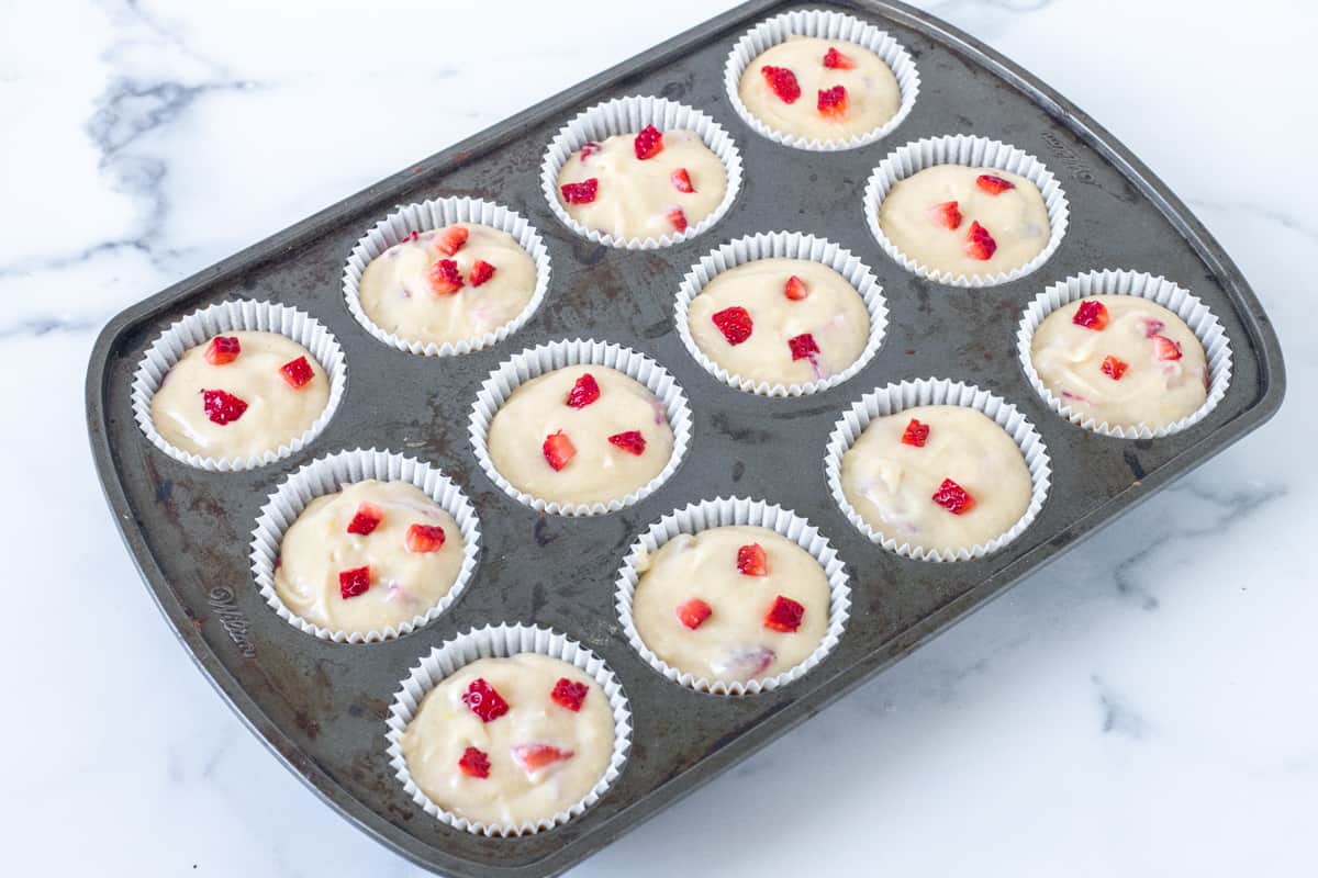 Muffin tin filled with strawberry muffin batter.