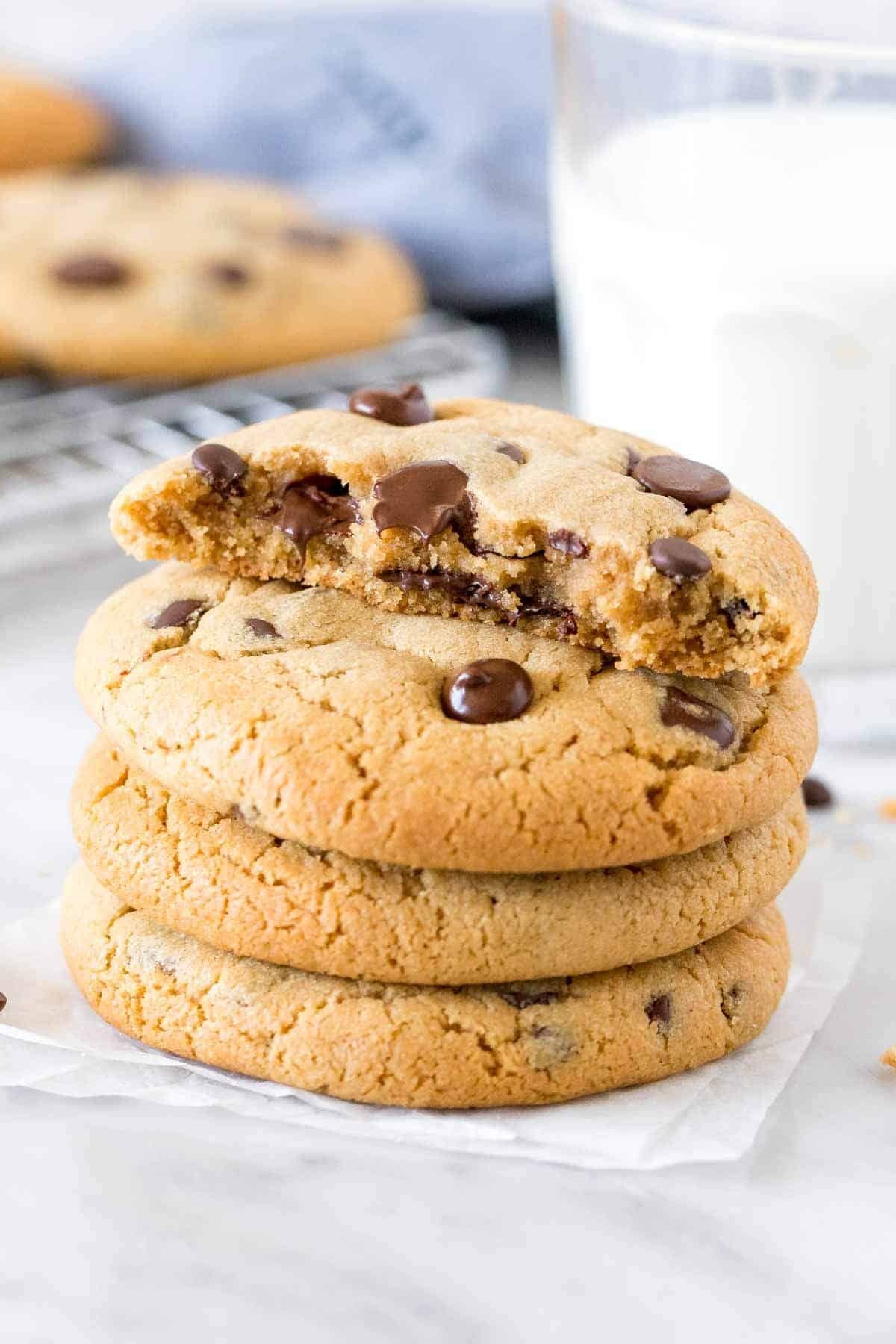 Stack of peanut butter chocolate chip cookies, with the top cookie broken in half. 