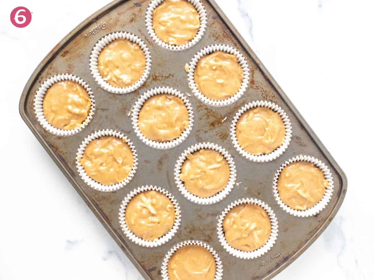 Apple cupcake batter spooned into lined muffin tin