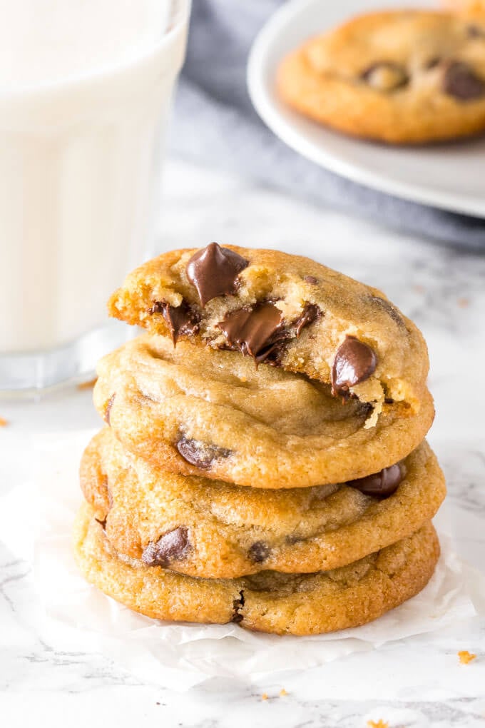 A stack of pudding chocolate chip cookies with one cookie broken in half to show the thick, extra soft center. 