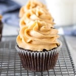 Chocolate cupcakes with peanut butter frosting on cooling rack with glass of milk.