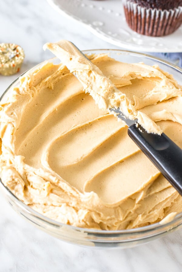 Bowl of peanut butter frosting with a knife on top of it. 