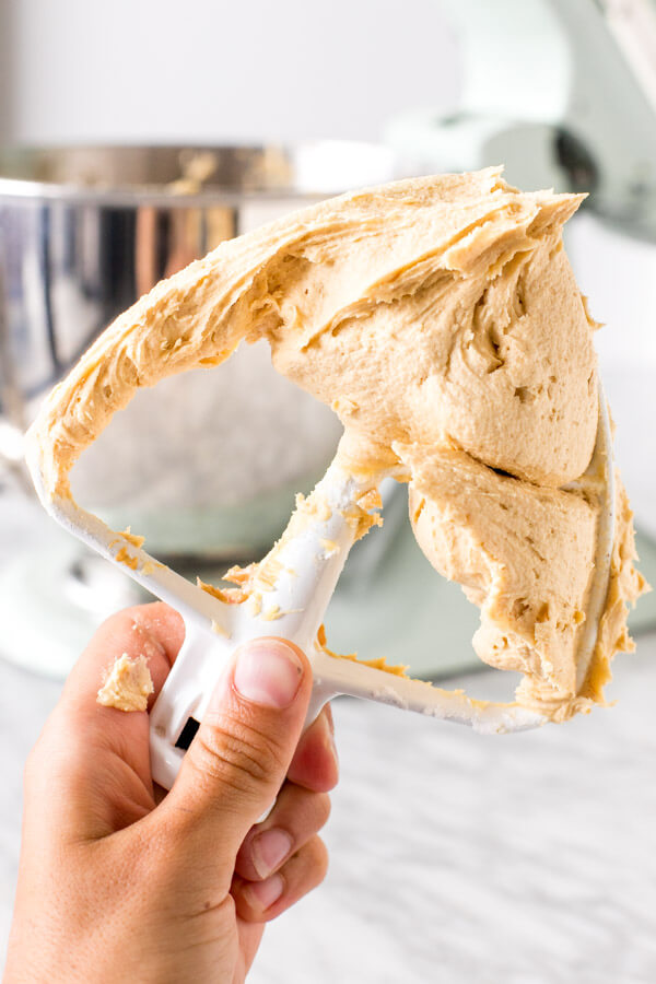 Stand mixer paddle attachment with peanut butter frosting on it. 