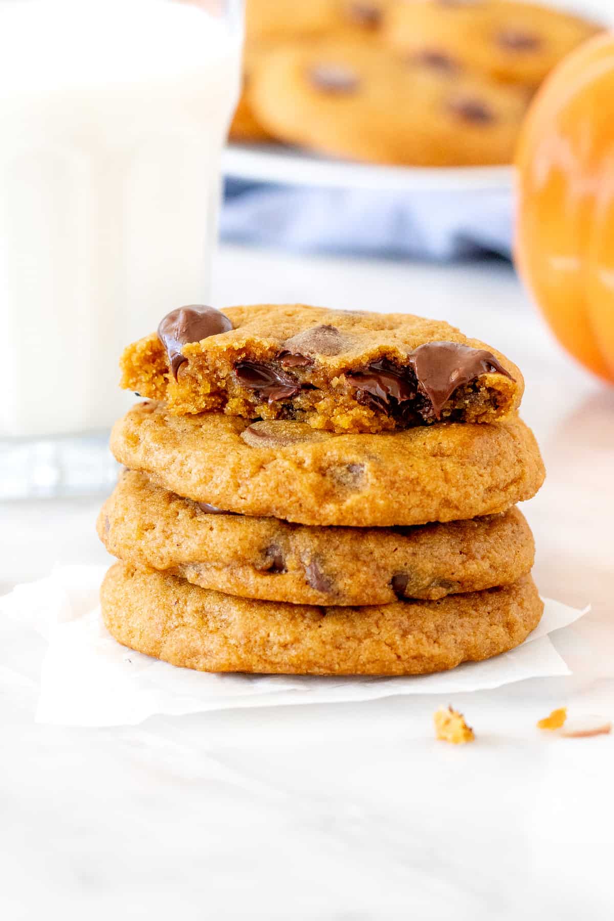 Stack of pumpkin chocolate chip cookies with glass of milk
