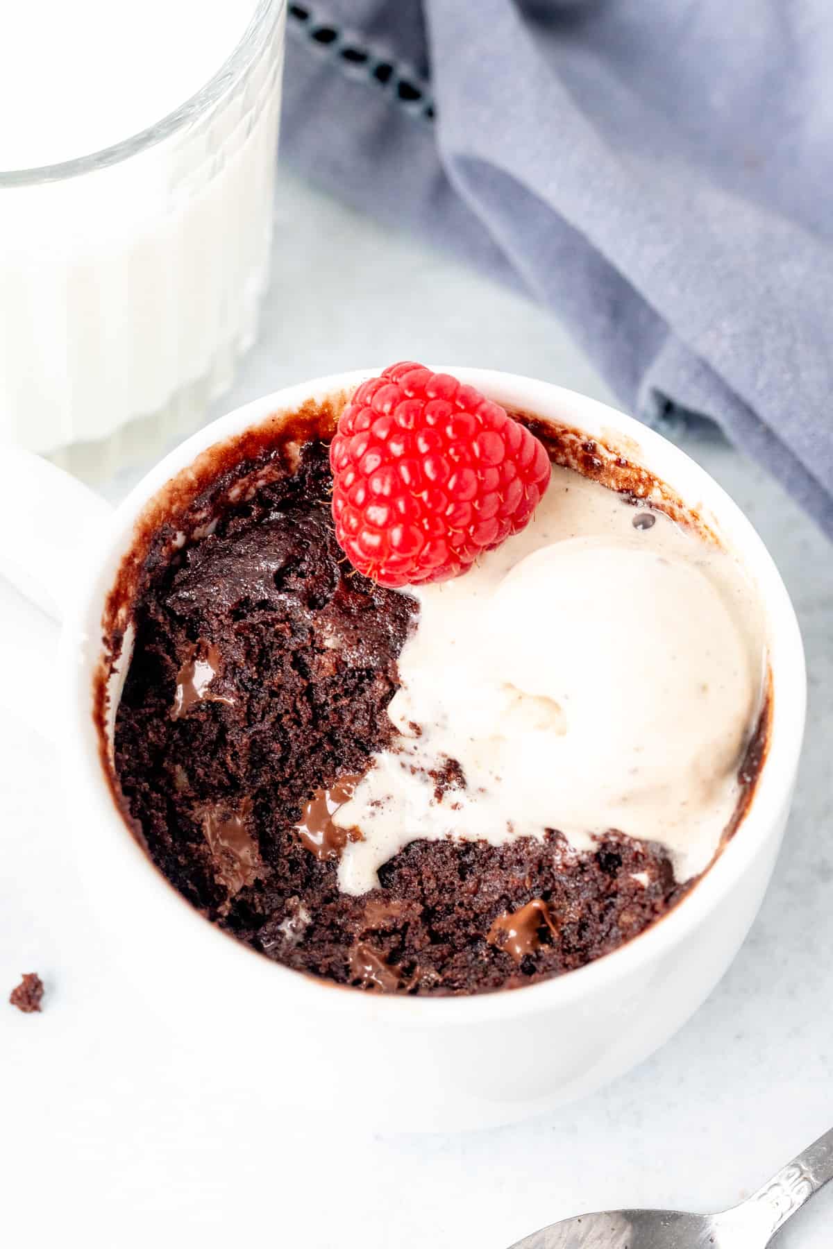 Chocolate mug cake with a scoop of ice cream with a bite taken out of it.