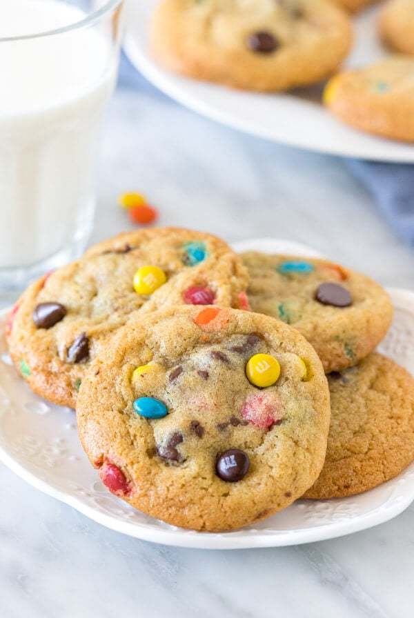 Plate of M&M cookies with a glass of milk. 