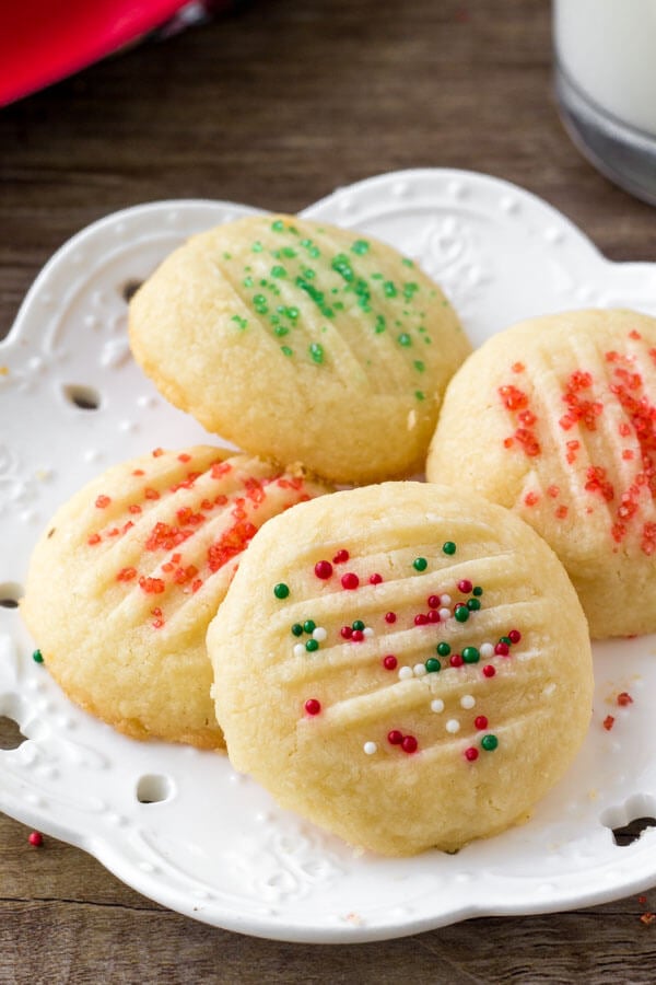 A plate of whipped shortbread cookies with holiday sprinkles. 