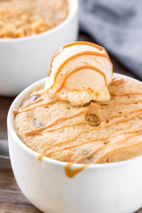 Peanut butter mug cake topped with ice cream and a drizzle of peanut butter